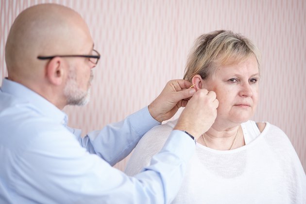 Arzt behandelt Patienten mit Akupunktur am Ohr im Rheumazentrum Rheinland-Pfalz