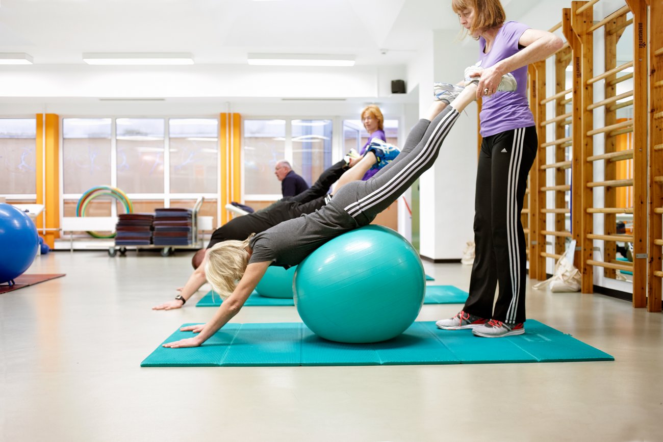 Patienten machen Rehaübungen für die Muskulator auf einem Gymnastikball - Rheumazentrum Rheinland-Pfalz
